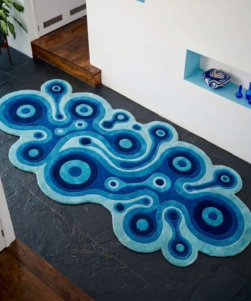 Wide overhead perspective interior lifestyle shot of the long Lagoon Loop abstract area rug styled on a black slate tile floor in a modern hallway next to a white wall.