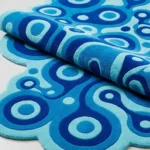 Close-up macro photograph highlighting the premium wool material loop texture, plush dimensional carving, and solid color blocks of the folded Lagoon Loop area rug.