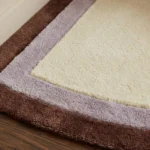 Low angle close-up floor perspective showcasing the plush hand-tufted pile and contrasting border lines of the Lilac Horizon rug.