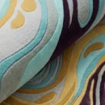 Close-up macro photograph highlighting the premium wool material texture, dense pile construction, and clean solid color blocks of the folded Luma River area rug.