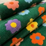 Detail photograph of the Meadow Bloom floral rug rolled over to showcase the thick, plush hand-tufted material texture and vibrant pile yarn.