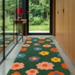 Wide perspective hallway lifestyle shot of the green Meadow Bloom runner rug styled on a concrete floor next to glass windows.