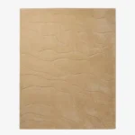 Full top-down product isolated shot of the rectangular Mira Sand area rug, featuring a subtle monochromatic design with organic wavy etched lines running across a solid warm sand beige field.