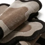 Close-up view of the folded Mocha Drift rug, showcasing the dense hand-tufted cut pile material texture and premium wool blend quality.