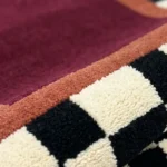 Detail photograph of the Montero Border rug folded over to showcase the high-quality pile depth and rich color contrast.