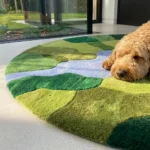 Low angle floor-level perspective showcasing the dense hand-tufted pile variations, rich green shades, and distinct carved borders of the circular Mossbrook area rug.
