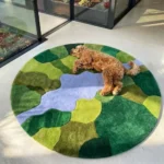 Wide perspective interior lifestyle shot of the circular Mossbrook abstract landscape rug styled on a modern concrete floor near floor-to-ceiling glass windows.