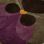 Close-up top angle perspective showcasing the premium hand-tufted pile variations, clean color block lines, and dimensional petal shape of the Plum Orchid area rug.