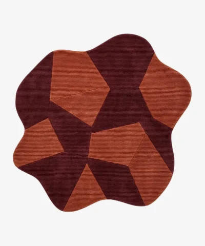 Custom-shaped fluid Prism rug isolated on a white background, featuring a fractured geometric pattern of interlocking burgundy and terracotta orange ribbed blocks.