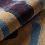 Close-up macro photograph highlighting the premium wool material texture and dense multi-level pile of the folded Sediment area rug.