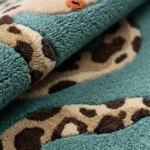 Close-up macro photograph highlighting the thick plush wool material texture, spotted pattern, and vibrant teal color of the hand-tufted Serpent Runner rug.