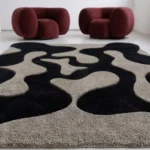 Wide overhead perspective shot of the black and gray Shadow Morph rug styled in a minimalist room with burgundy chairs.