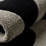 Close-up macro photograph highlighting the thick, plush wool material texture and organic wave patterns of the Shadow Morph rug.