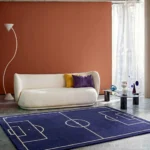 Wide perspective interior lifestyle shot of the navy blue soccer field area rug styled in a boy's bedroom with soccer-themed decor.