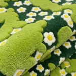 Close-up macro photograph highlighting the thick hand-tufted wool material texture and distinct multi-level pile of the folded Terrain Bloom rug.