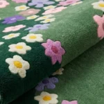 Close-up macro photograph highlighting the premium hand-tufted pile texture and vibrant dimensional floral details of the folded Wildflower Meadow rug.