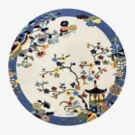 A top-down studio product photograph of the round Celadon area rug, featuring an intricate Chinoiserie-inspired floral and pagoda motif in a vibrant, multi-colored palette against a creamy off-white background.