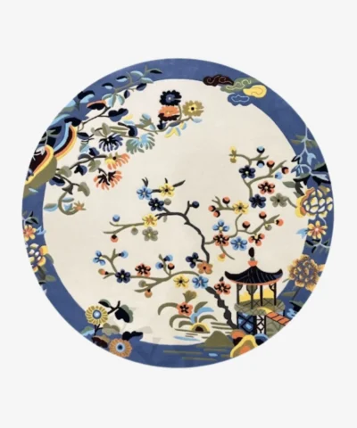 A top-down studio product photograph of the round Celadon area rug, featuring an intricate Chinoiserie-inspired floral and pagoda motif in a vibrant, multi-colored palette against a creamy off-white background.