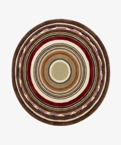 A top-down studio product photograph of a round area rug featuring concentric circular patterns in rich tones of chestnut, deep red, cream, and purple, displayed on a clean background.