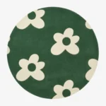 Full top-down product isolated shot of the round Floreo area rug, showcasing a playful retro pop art daisy motif with off-white flowers scattered across a vibrant forest green field.