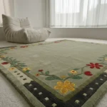 A low-angle surface shot focusing on the corner of the Florivert light green rug, showcasing a tufted yellow flower and a dark geometric outer border against a white floor setting.