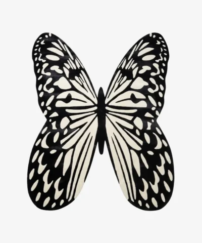 A top-down studio product photograph of the Monarch Noir area rug, featuring a striking, hand-tufted butterfly silhouette in high-contrast black and off-white.
