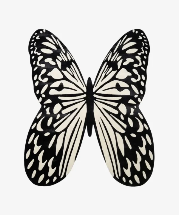 A top-down studio product photograph of the Monarch Noir area rug, featuring a striking, hand-tufted butterfly silhouette in high-contrast black and off-white.