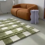 Floor-level side angle perspective showcasing the architectural shaggy details, clean block borders, and contemporary green and white color palette of the Moss Interlace checkered rug.