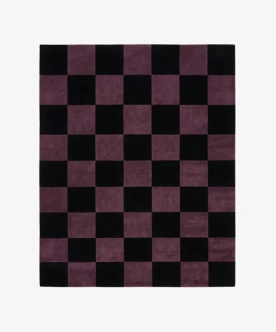 A top-down studio product photograph of a rectangular area rug featuring a classic checkered pattern in mulberry purple and black.