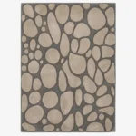A top-down studio product photograph of a modern rectangular area rug featuring an organic stone pattern with beige pebble shapes set against a dark gray base.