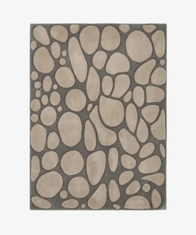 A top-down studio product photograph of a modern rectangular area rug featuring an organic stone pattern with beige pebble shapes set against a dark gray base.