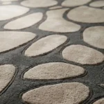 A detailed interior perspective shot focusing on the textured pebble motifs and modern furniture placement on the Riverstone area rug.