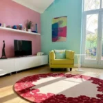 Low-angle room view perspective emphasizing the large geometric circular shape, plush hand-tufted pile uniformity, and vibrant flat 2D color blocks of the Rosara floral accent rug in the sunlight.
