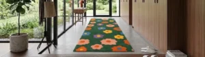 Wide perspective interior lifestyle view of long runner rugs in hallways, featuring a vibrant dark green field adorned with retro 1970s pop art flower shapes in solid orange, pink, yellow, blue, and purple color blocks styled on a modern concrete floor.