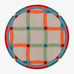 A top-down studio product photograph of the round Sage Plaidor area rug, featuring a neutral beige base with an intersecting grid pattern in vibrant orange, sage green, and blue, framed by a multi-colored circular border.