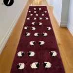 Perspective interior view of a deep burgundy wool runner rug with a repeating sheep pattern, placed in a hallway setting.