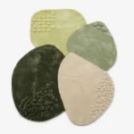 Full top-down product isolated shot of the custom-shaped Zen Pebble area rug, featuring overlapping organic stone contours with raised bubble clusters in an earth-toned palette of forest green, sage, lime, and sand beige.