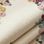 Folded view of the Bloomara tufted rug highlighting the high-density plush wool pile, cream background, and detailed botanical floral tufting.