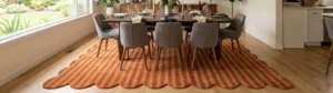 Dining Room Table Rug featuring an orange and rust striped pattern with a scalloped edge, styled under a modern dining table and chairs in a bright open-plan home.