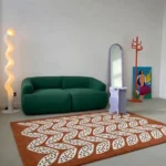 Folivora Leaf botanical pattern area rug styled in a modern living space with a green sofa and contemporary decor.