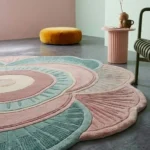 Angle view of the handmade Palestra floral rug highlighting its scalloped flower shape, textured carving, and cozy room setting.