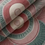 Close-up of the plush tufted pile texture, carved contours, and soft pink and teal color palette on the Palestra rug.