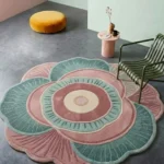 Palestra round floral designer area rug styled in a modern living space with a green chair, pink side table, and yellow pouf.