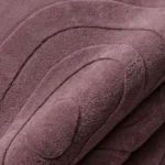 Close-up of the plush tufted pile texture, rich dusty plum tone, and carved dimensional lines on the Plumique Basin rug.