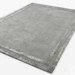 Perspective product view of the Gray Edge wool rug, displaying the rich gray tone and the sophisticated framed border on a clean background.