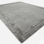 Angled studio product view of the rectangular Gray Edge rug, highlighting its plush grey pile and textured double border design.