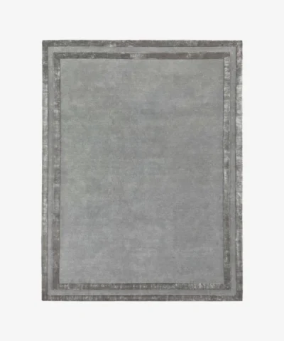 Studio flat-lay product photograph of the rectangular Gray Edge rug on a clean background, showcasing the solid grey wool field framed by double contrasting metallic silver borders.