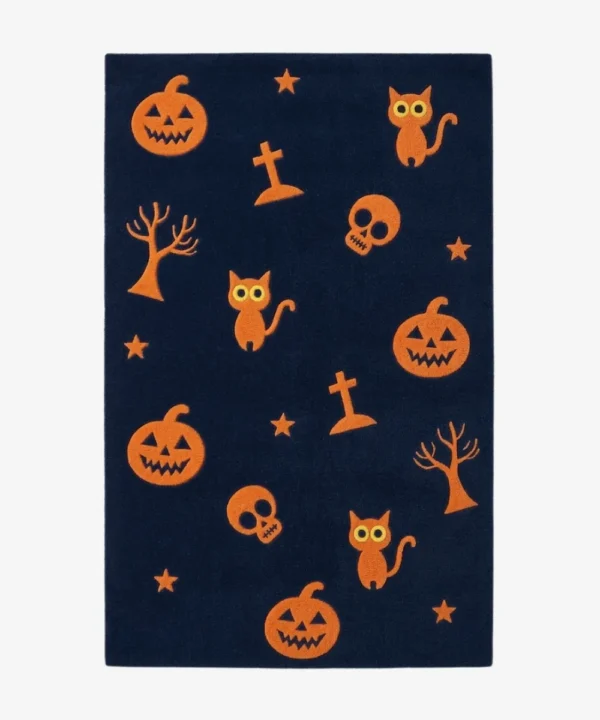 Studio flat-lay product photograph of the rectangular Jack-o’-Lantern Jamboree rug on a clean background, showcasing the dark navy blue wool field patterned with smiling jack-o'-lantern pumpkins, black cats, skulls, gravestones, and stars.