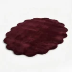 Angled studio product view of the cloud-shaped Ruby Cloud rug, highlighting its plush burgundy pile and distinctive scalloped silhouette.