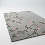 Low-angle studio perspective of the grey Sakura Branch wool rug against a clean background, highlighting the plush pile and trailing floral cherry blossom design.